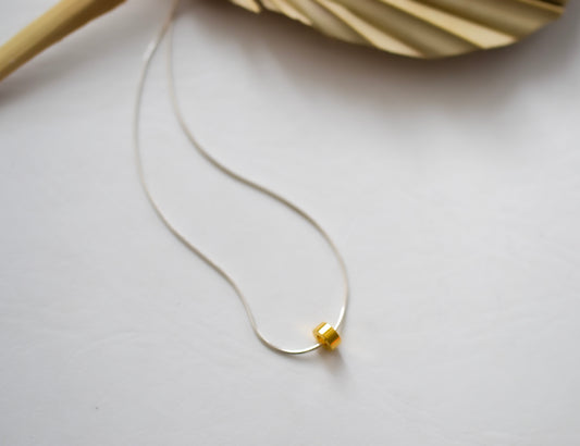 sterling silver chain with simple gold disc in center against white backgroun