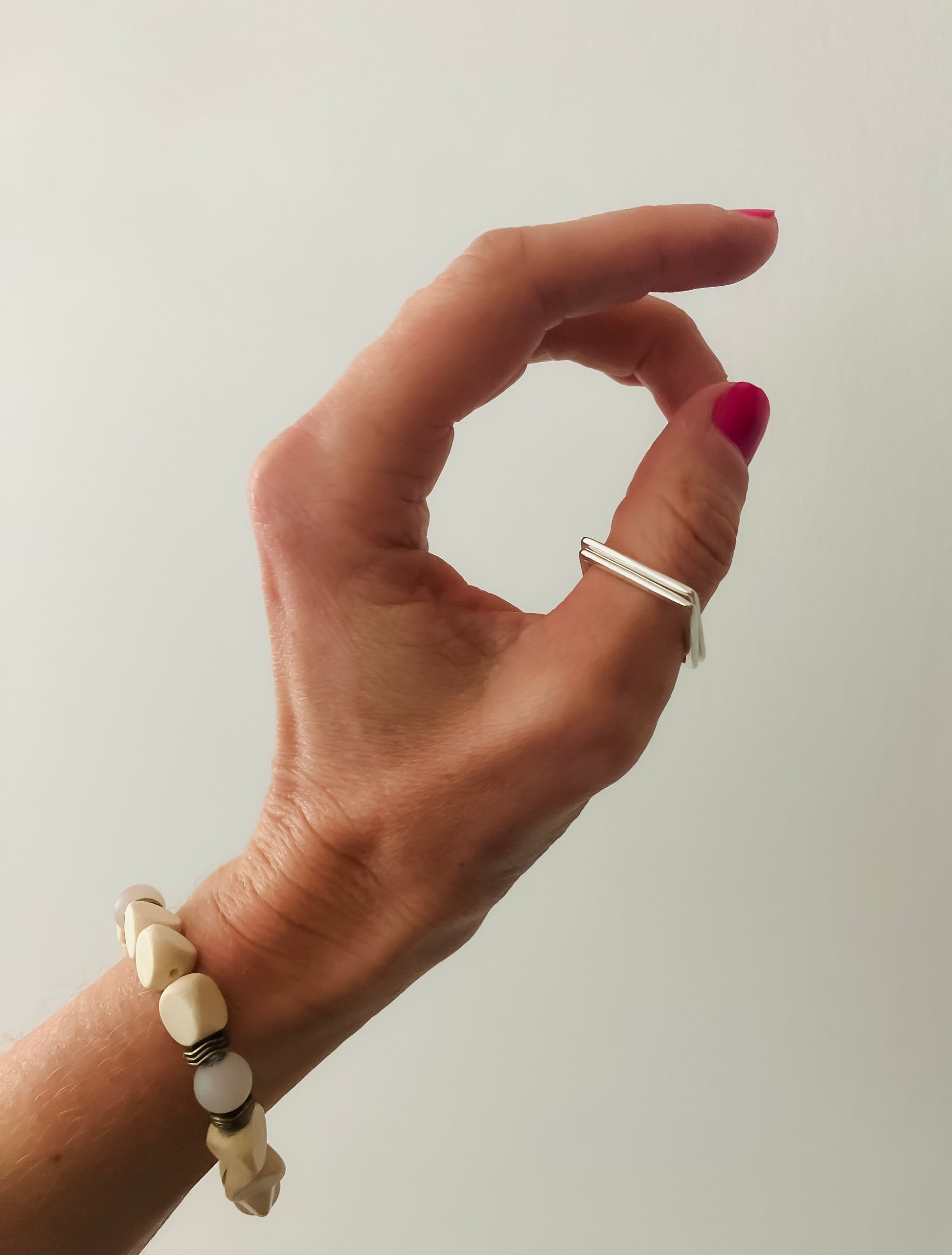 woman left hand wearing a square sterling silver ring and beaded bracelet 