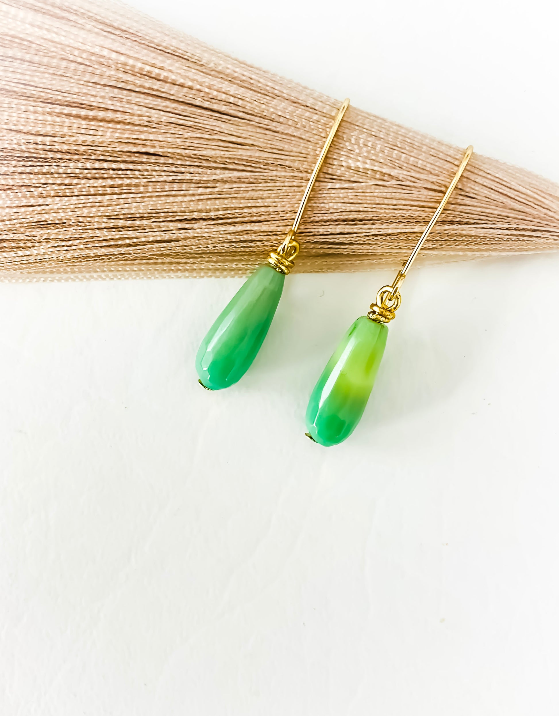 Seafoam Green Chyrophase oval shaped gold fill earrings against dried wheat grass